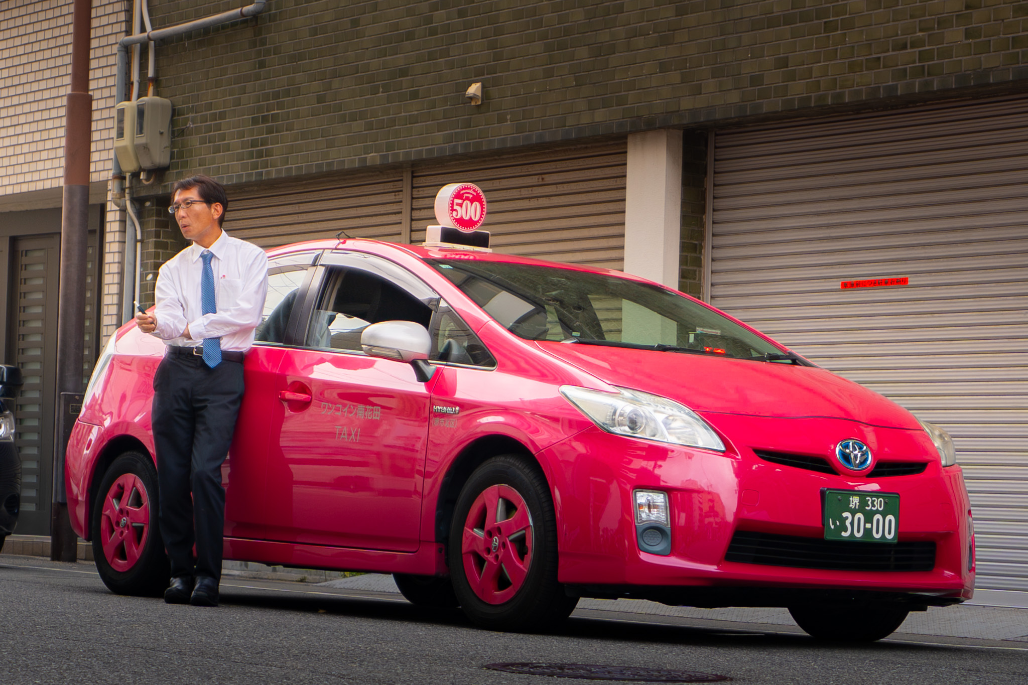 Taxi driver standing beside a pink taxi in Japan